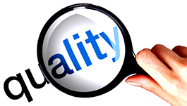 A hand holding a magnifying glass focusing on the word ''quality.''